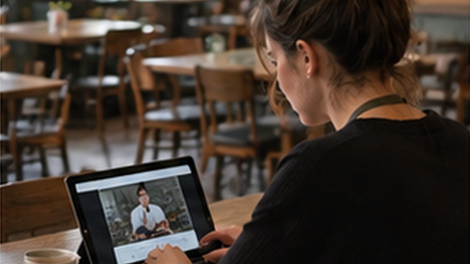 Staff member taking an online food hygiene course on a tablet in an empty restaurant